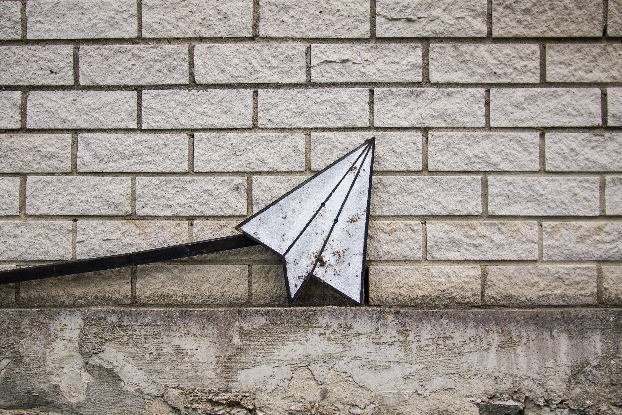 paper airplane in front of a brick wall